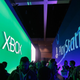 Visitors walk past giant signs of Xbox and PlayStation at an E3 conference.